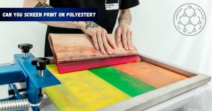 Person screen printing colorful design on polyester fabric using a squeegee and mesh screen.