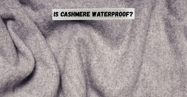 Close-up of soft grey cashmere fabric with the text “Is Cashmere Waterproof?” written across it.