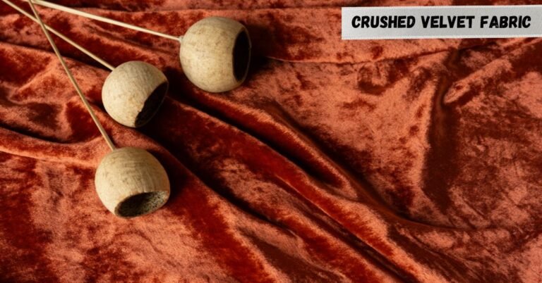 What is crushed velvet fabric? Close-up of rich orange crushed velvet with wooden decorative objects.