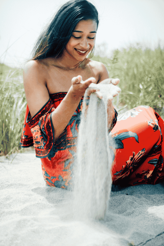 A woman on a Nantucket beach in a vibrant floral summer dress, exemplifying a relaxed casual outfit.