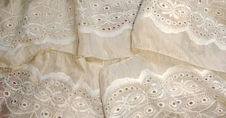 Close-up of beige Cotton Eyelet fabric with oval and circular embroidery patterns