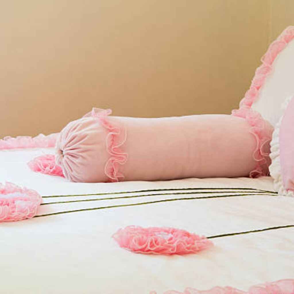 Pastel pink bedsheets with ruffles in a cozy, shabby-chic setup.